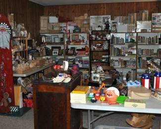 This room is enormous!  This half is filled with children's books, games and puzzles, office supplies, tole painting supplies, Ikea storage containers, craft supplies, dressers, tall multi-drawer cabinet, printer, craft kits, boxes, frames, antique children's desks, red/white/blue decorations, bee collectibles, pails, rocking horses, children's furniture, dining chairs, stuffed animals, baskets, and sooo much more!