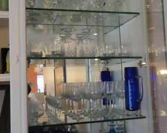 Shelves filled with crystal stemware, decanters and blue glass.