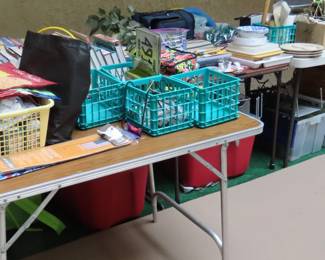 Tables of books, tools, picnic sets, baskets, plastic tubs. 