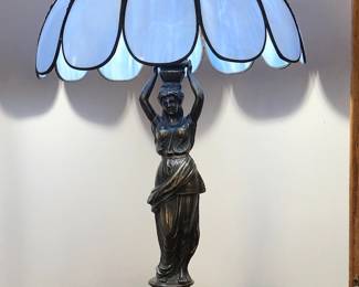 Brass figural table lamp with stained glass shade.