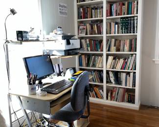 Computer, desk, desk chair, library of books, some office supplies