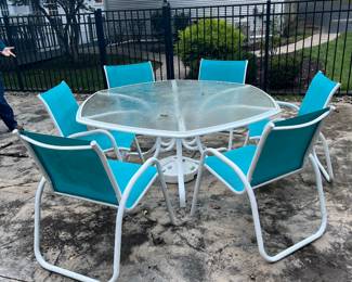 Outdoor patio set. Glass table and six colorful chairs.