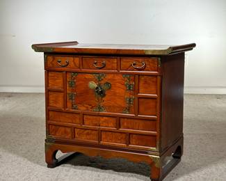 CHINESE DIMINUTIVE CABINET | Small, ornate wooden cabinet with three pull-out drawers over two cabinet doors. Smooth, tiger-striped wood grain with warm red tones. The center features a decorative metal butterfly clasp. - l. 27 x w. 17 x h. 24 in