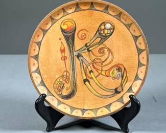 HAND PAINTED DECORATIVE WOOD PLATE | Colorful hand-painted wooden plate with a green felt protective backing. Featuring an elegant knotted design in the shape of the letter "K" and a rounded, sun-shaped border. Celtic design, adapted from the Book of Lindisfarne. - dia. 7 in