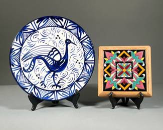 (2PC) DECORATIVE CERAMICS | A colorful decorative tile in wood frame with a geometric floral design in red, black, pink, orange, and yellow, accompanied by a decorative Spanish white-and-blue plate with peacock, signed P. Zouille. - dia. 12 in (largest)