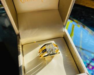 DIAMOND RING:
One 18K yellow gold diamond ring featuring one cut-cornered rectangular modified brilliant "radiant cut diamond of 4.02ct, thirty (30) round full cut diamonds and two (2) princess cut diamonds aii totaling 0.80ct. The radiant cut diamond is center bar set with diamonds channel set down the center of each open shoulder and one princess flush set on each profile. The 11.8mm high polish Euro shank tapers to 5.4mm at the back and features inside soldered sizing bars.