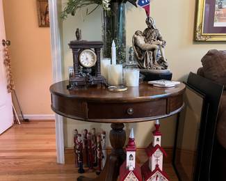 Plastic red roof churches, drum table, tall flower arrangement, carved wooden Santas, clock