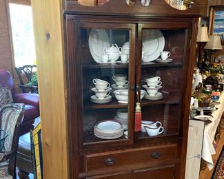 Corner china cabinet full of various china patterns.