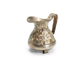 1256
Mid-20th century
A Mexican Alpaca Silver Water Pitcher
Stamped to underside: Hecho en Mexico / Alpaca
The alpaca silver pitcher decorated with inset abalone shell set on three curvilinear feet
8.625" H x 9.75" W x 7" D
Estimate: $200 - $300