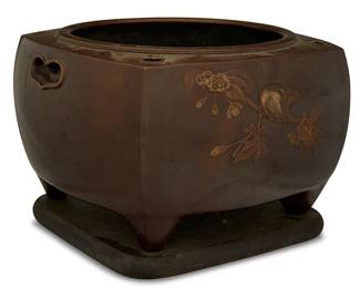 1345
Mid/late 20th century
A Japanese Bronze Hibachi
Appears unmarked
The cast bronze footed vessel decorated with a bird alighted on a cherry blossom branch in low relief to either side and set upon a wood base
9" H x 13" Dia.
Estimate: $100 - $150