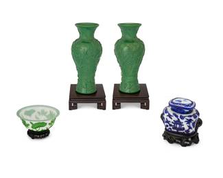 1365
20th century
A Group Of Chinese Peking Glass
Each appears unmarked
Comprising a near pair of green molded glass baluster-form vases with cherry blossom motifs, each set upon a squared wood stand, one cameo-style green and white glass bowl set upon a carved wood stand, and one cameo-style blue and white lidded glass jar with opposing guardian lion opposing handles set upon a carved wood stand, 8 pieces
Largest: 11.5" H x 4.5" Dia.; smallest with stand: 6.75" H x 5.75" Dia.
Estimate: $300 - $500