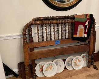 antique wood bed frame, large antique wall mirror in black and gold, quilt, display plates with fruit
