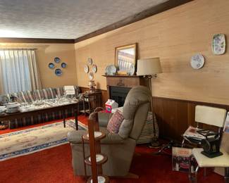 decorative plates, beige and blue area rug, vintage furniture, antique side table display, blue/white/black plaid couch, plates, serving pieces