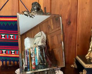 antique hardwood chest of drawers, embroidered wall art, decorative clock with statue, antique mirror with bronze figurine