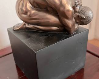 Male nude statue on base.