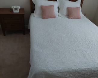 full-size bed with headboard, bed side table, and comforter