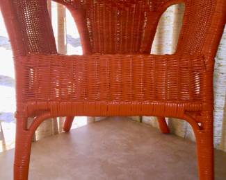An orange wicker chair beckons folks to relax. 