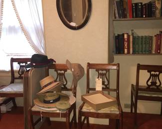 A set of lyre-back chairs get a timeout from dining duties while nestled below a framed oval mirror. 