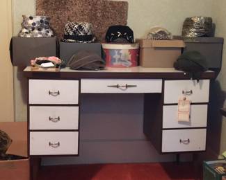 A desk with original hardware and white drawers. Here, it gets a better than business task of holding fancy vintage hats. 