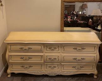 There is a nice white dresser prominently displayed here, and a bit of a framed mirror behind it.