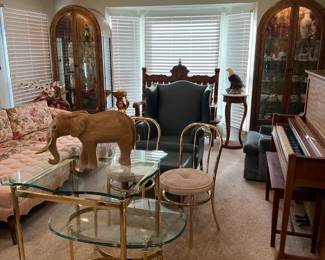 This living room has a lot going for it.  The upright piano is one of the items.  A pair of display cabinets grace both sides of a doorway.  A glass-topped table sits foreground.