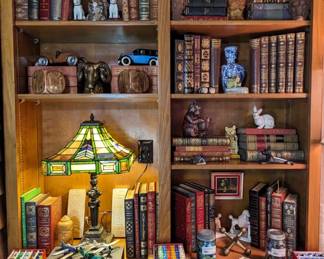 Close-up of one of the bookshelves, with the leather-bound books, vintage and antique, Tiffany-style stained glass lamp, marbles and cast iron collection. 