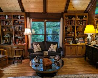 Asian inspired, glass-topped faux tortoise coffee table, geode collection, pair of MCM armchairs, antique mahogany bookshelf step stool, black leather Natuzzi loveseat, vintage and antique leather books and cast iron collection; another Amy Dandy original oil on canvas.