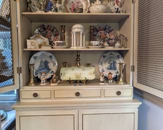 English brass candlesticks, German and English porcelains Hummel figurines, Asian porcelain charger on stand, hand-carved wooden Buddha and vintage wedding cake topper pair.