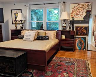 The owner of this bed is 6'7" (think Myra Breckinridge) so he custom ordered a king size bed to handle the size.  The bed and matching dresser was made and signed by John Provence, of Heirloom Artisans in 2004.    (https://www.shoppeheirloom.com/).                                    The headboard curves slightly to form two built-in side tables, with plenty of storage for your boudoir needs. There's also a matching dresser, a rare Asian-themed Lane cedar chest, pair of vintage Greek-themed porcelain table lamps, more Amy Dandy art, all atop a luscious, vintage hand-woven Persian Bakhtiari, measuring 10' x 12' 2".