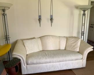 White sofa, metal torchiere floor lamps, metal art wall sconces 