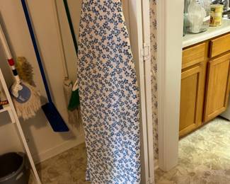 Ironing board and mops/brooms in laundry room closet