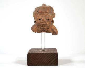 ANCIENT STATUE ON STAND | Fragment of an ancient clay statue mounted on an acrylic and wood stand. - l. 3.5 x w. 3 x h. 7 in.