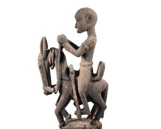 AFRICAN CARVED WOOD FIGURINE | Showing man riding horse with elongated face mounted to black stand. - l. 12.5 x w. 8 x h. 24 in
