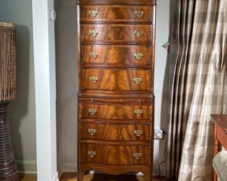 GEORGE III STYLE MAHOGANY SERPENTINE TALL CHEST | English, 19th/20th-century flame mahogany veneer with brass pulls, having an upper section with four drawers, over a lower case with brushing slide and three drawers, over a scalloped skirt and flaring feet. - l. 16 x w. 25 x h. 65.25 in