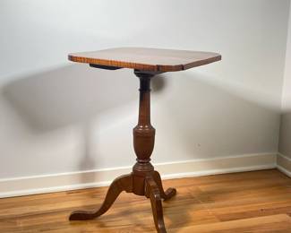 FEDERAL TIGER MAPLE TILT-TOP CANDLE STAND | Square top with shaped corners above a vasiform standard on tripod base with snake feet. - l. 17.75 x w. 17.75 x h. 25.5 in