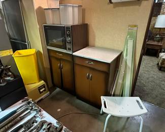 In the back are two SWEET vintage metal kitchen cabinets with formica tops! A vintage microwave! In the middle of the picture, down on the floor is a GREAT camping toilet! 