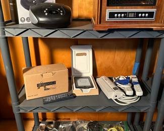 An entire room full of electronics big and small! ALL work! Many in their original boxes! Small handheld radios, Vintage Sony Walkman, CD players, Amazon Kindle, Heaters and MORE! (Note bottom shelf is FILLED with cords of every shape and size!)