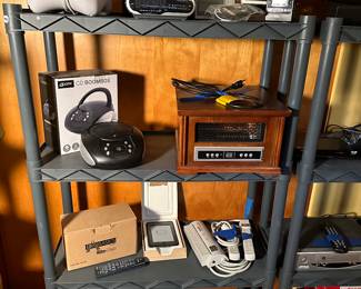 An entire room full of electronics big and small! ALL work! Many in their original boxes! Small handheld radios, Vintage Sony Walkman, CD players, Amazon Kindle, Heaters and MORE! (Note bottom shelf is FILLED with cords of every shape and size!)