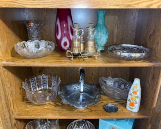 Cut and decorative glass serving pieces along side beautiful red and green art glass vases