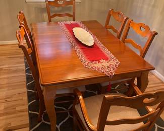 Beautiful solid wood Bassett dining room table with six chairs two leaves, table cover and area rug.