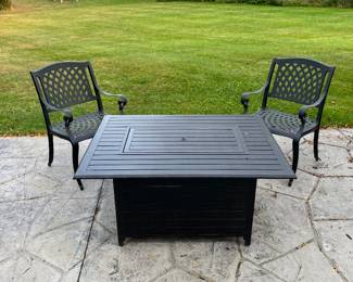 Propane fire pit with two matching iron chairs.