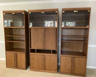 set of three wood bookshelves with wooden and glass-front cabinet doors.