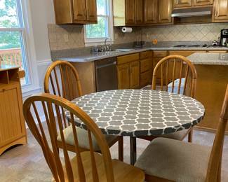 Round kitchen table with gray and white pattern, four wood chairs