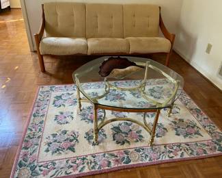 mid-century modern beige and hardwood sofa, mid-century modern brass and glass-top coffee table, blown glass dish, pink and green floral area rug