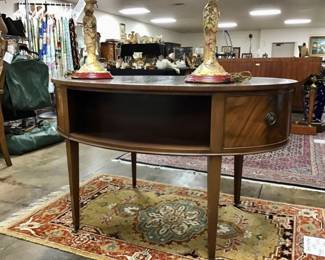 Vintage flame mahogany tooled leather top writing desk by Baker furniture. Single drawer flanked by two fitted letter compartments on either side. Display shelf on cabinet front.