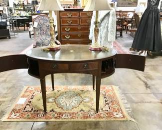 Vintage flame mahogany tooled leather top writing desk by Baker furniture. Single drawer flanked by two fitted letter compartments on either side. Display shelf on cabinet front.
