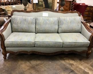 Masterfully, crafted and regally designed SCHNADIG sofa. Curved top with carved wood design on front and back, canned sides, and lovely designer upholstery. 