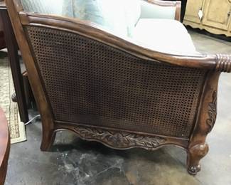 Masterfully, crafted and regally designed SCHNADIG sofa. Curved top with carved wood design on front and back, canned sides, and lovely designer upholstery. 