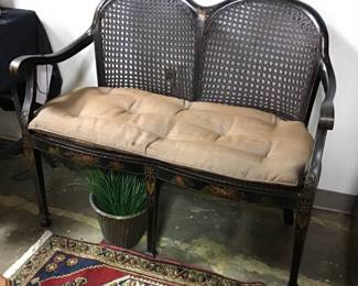 Chinoiserie Settee. Double caned back and seat, black lacquered with gilt decorations, and raised landscape scenes. 