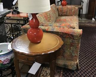 Round French Provincial leather top table with gold gilding. One drawer. There are two of these available.  Orange double gourd style, ceramic lamp. There are two of these available.